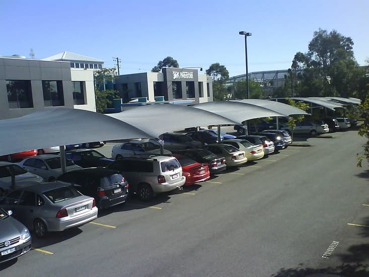 A large shade structure covering commercial car park spaces